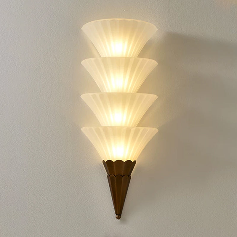 Four-cone Clérachic wall sconce, the tallest version, lit warm with each ribbed glass cone glowing above a brown base.