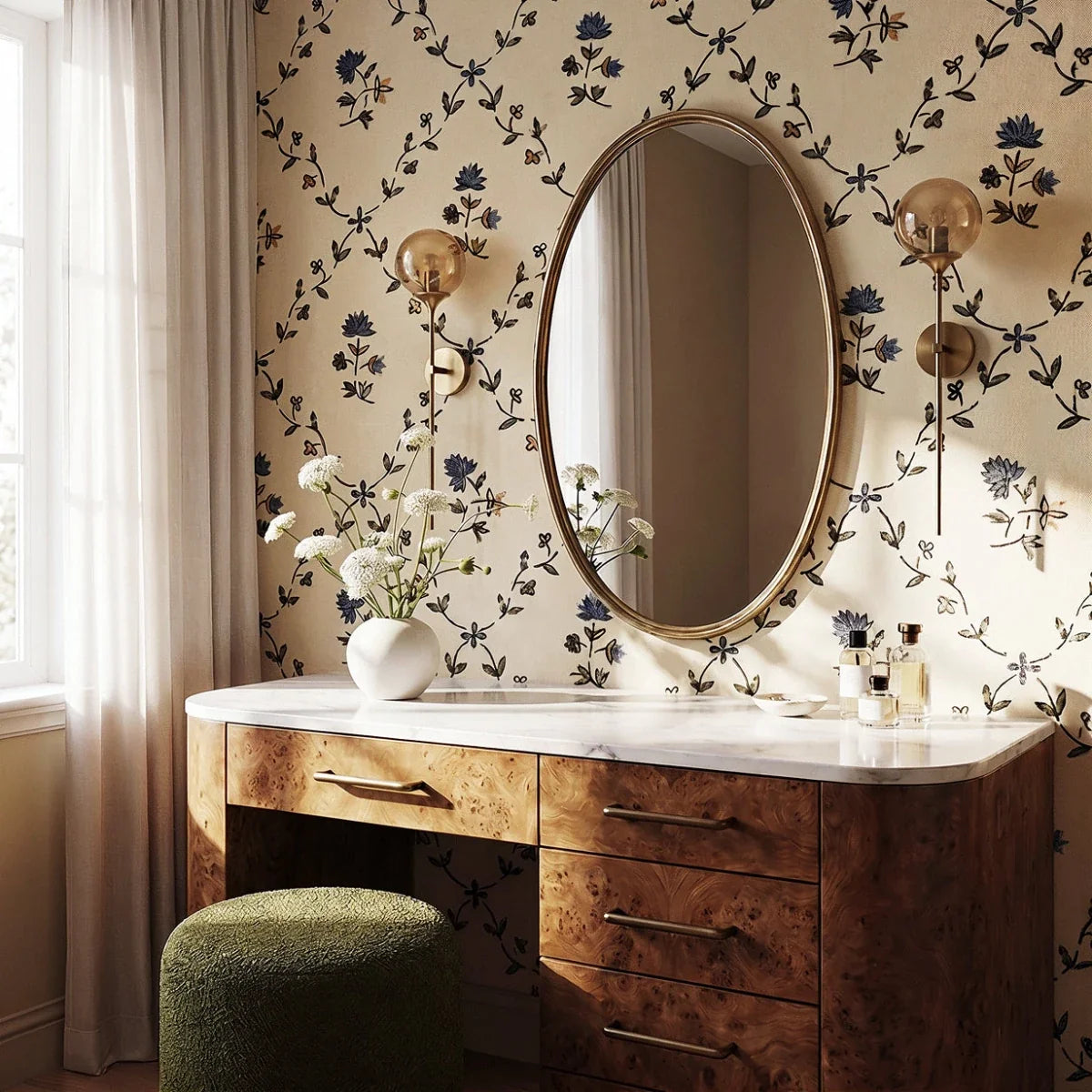 Clérachic brass wall sconces with amber glass globe shades flank an oval mirror above a burl wood vanity, floral wallpaper backdrop.