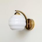 Clérachic gold wall sconce with a white ribbed lantern shade, shown in side profile on a plain studio backdrop.