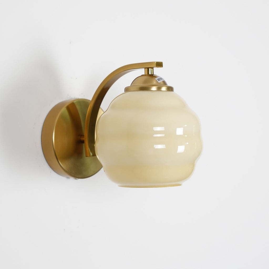 Studio shot of the Clérachic lantern wall sconce in gold with a beige glass shade and circular backplate.
