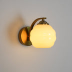 Clérachic gold wall sconce glowing through a white ribbed lantern shade, a soft shadow on the white wall.