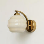 Clérachic gold wall sconce in side profile on a white wall, the beige lantern shade showing its ribbed glass.