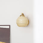 Looking up at the Clérachic gold wall sconce and beige lantern shade on a white wall, art just in frame.
