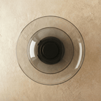 Clérachic round wall light with concentric smoky grey glass discs around a dark centre, switched off, on limewash plaster.