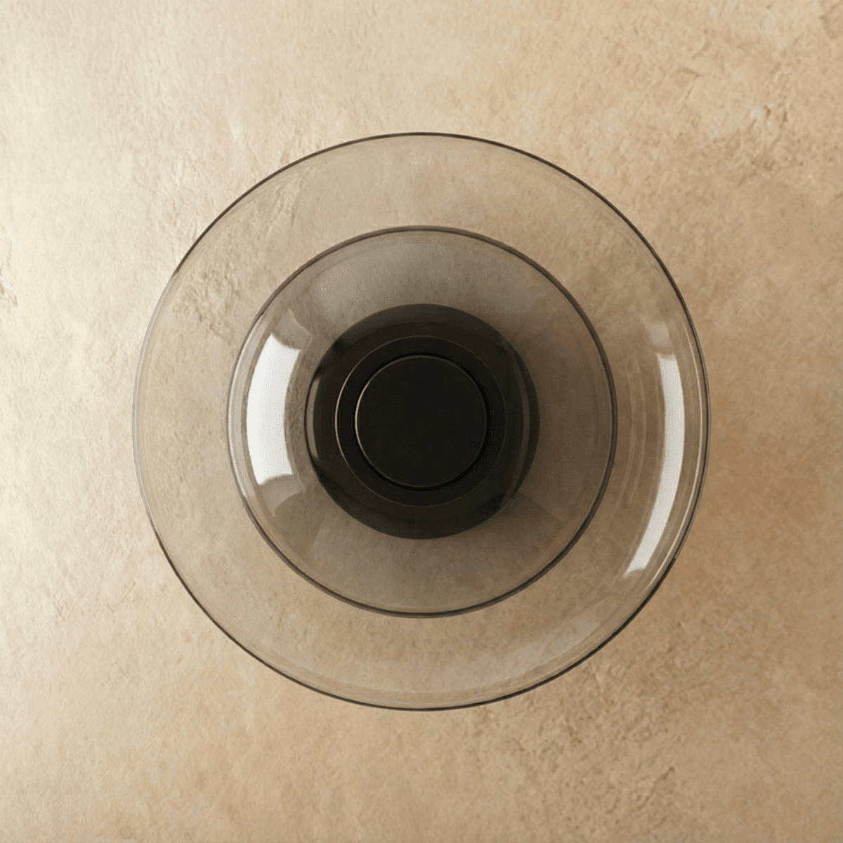 Clérachic round wall light with concentric smoky grey glass discs around a dark centre, switched off, on limewash plaster.