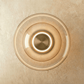 Clérachic round wall light of concentric cognac-tinted glass discs with a glowing ring around a brushed brass centre.