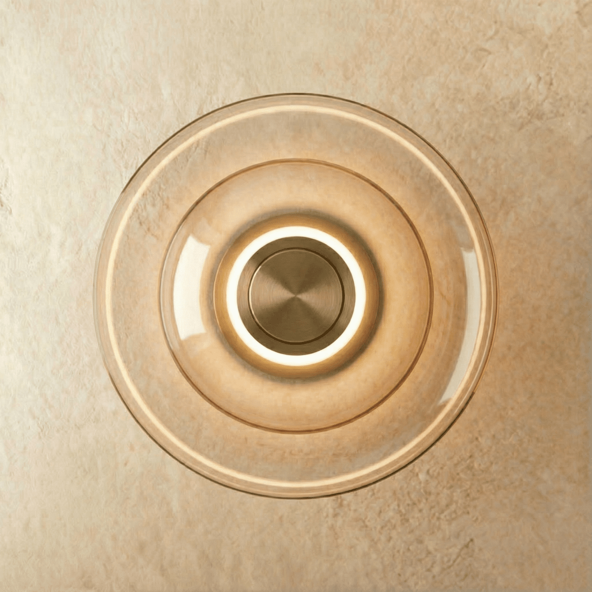 Clérachic round wall light of concentric cognac-tinted glass discs with a glowing ring around a brushed brass centre.