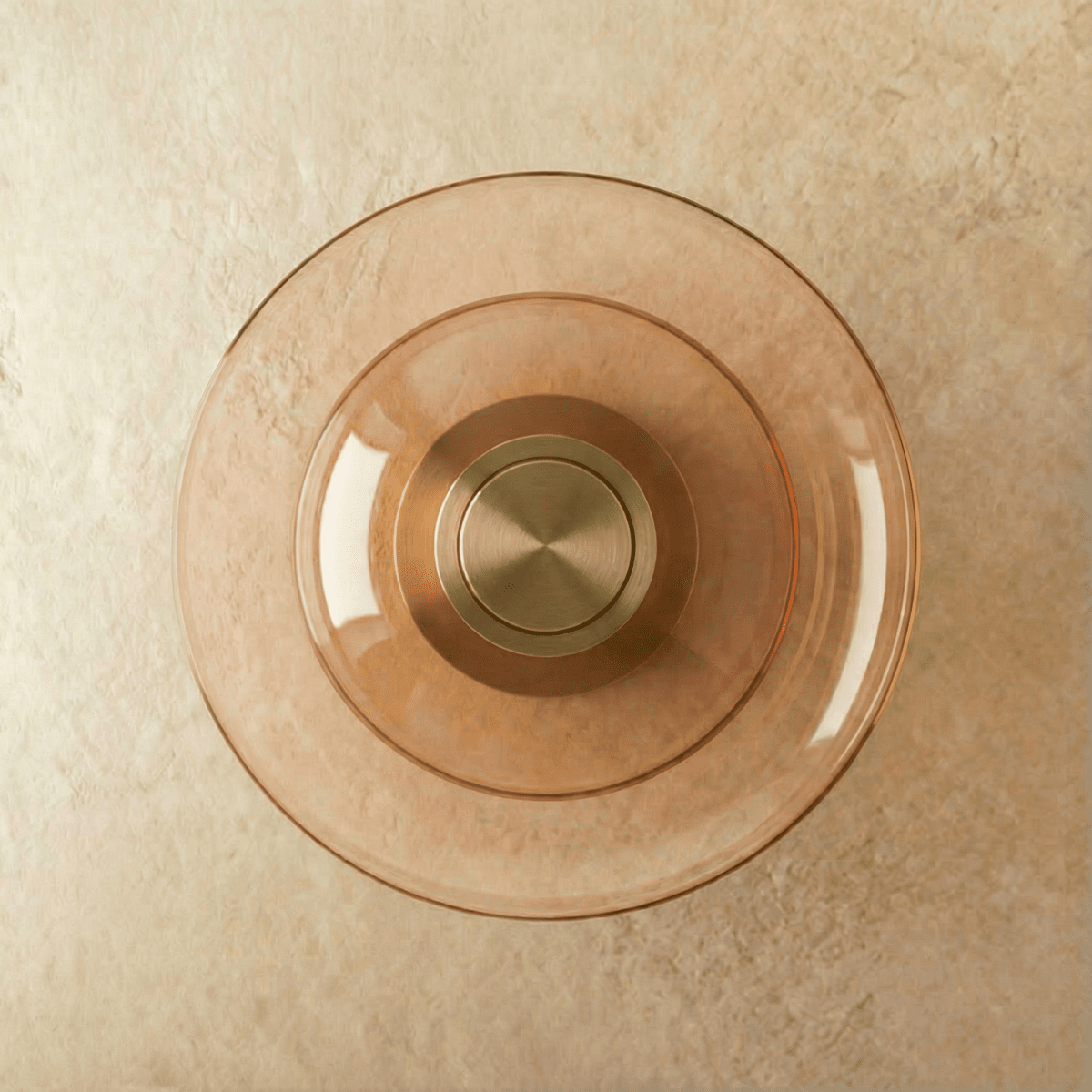 Clérachic round wall light with layered cognac glass discs around a brushed brass centre, unlit, on limewash plaster.