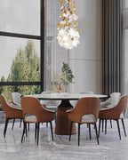 Over a round marble dining table with tan leather chairs, a small round Clérachic chandelier of white petals hangs near a tall window.