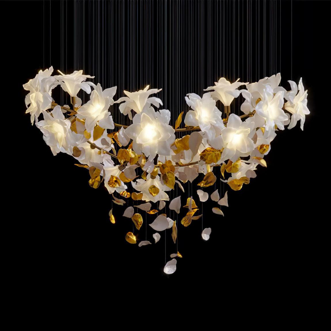 On black, this Clérachic chandelier spreads wide in a curved bowl of lit white petal flowers with brass leaves and a few dropped petals.