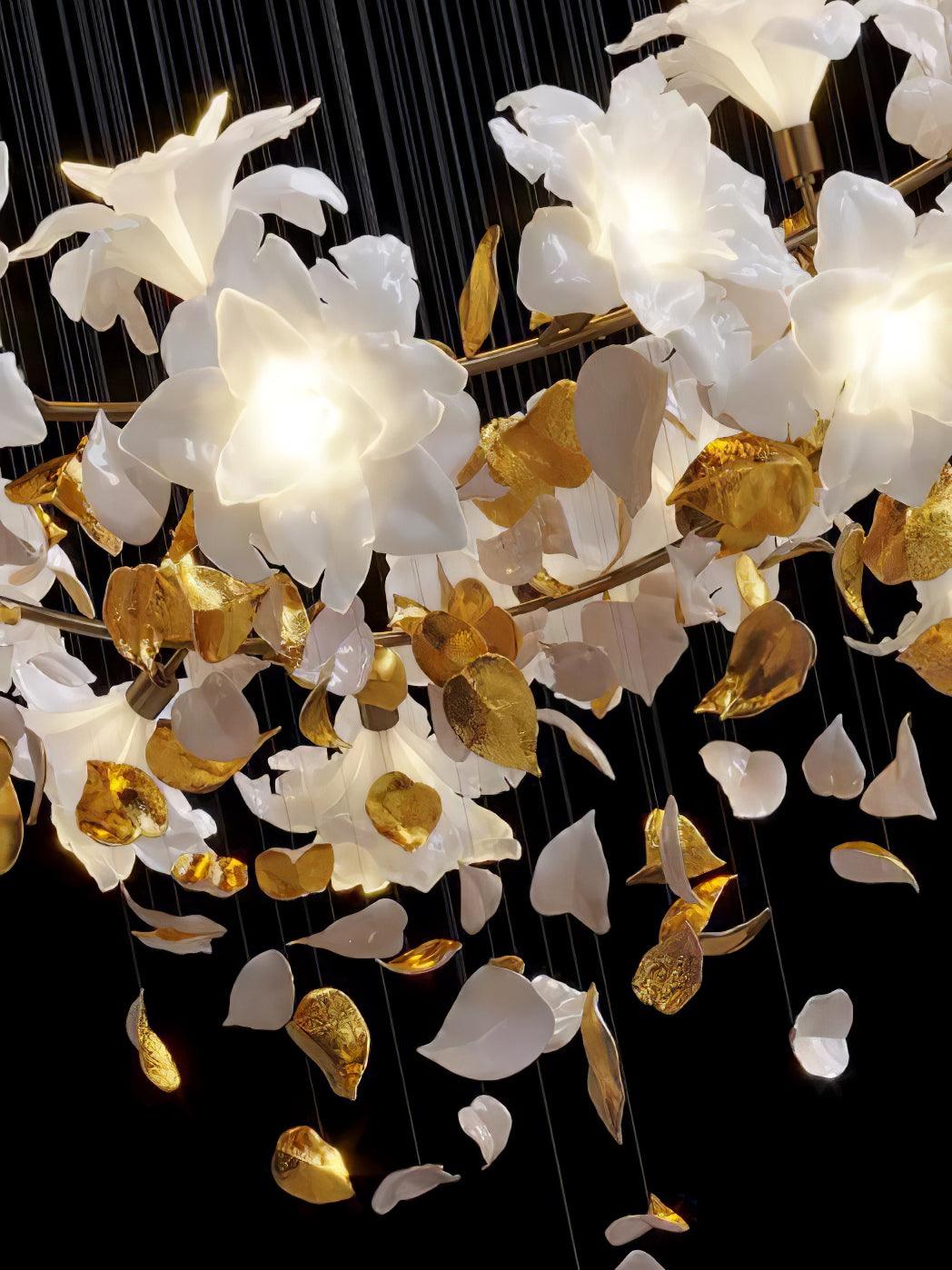 Close view of lit white petal blooms on a brass ring, with loose white and gold leaves hanging below, on this Clérachic chandelier.