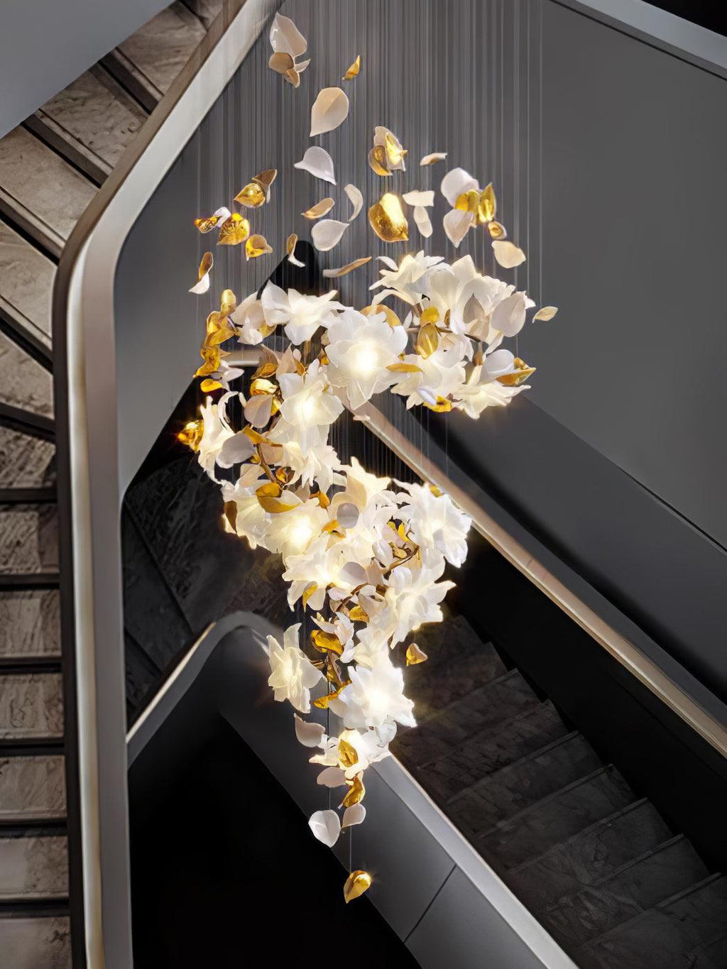 From a high angle over a dark stair, this Clérachic chandelier trails white petals and brass leaves in a lit double curve.