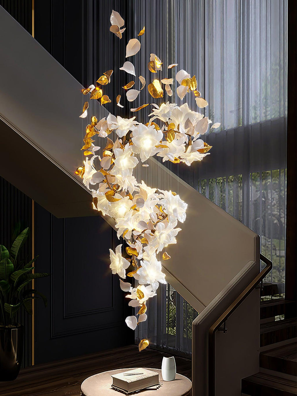 Above a round side table with a book and a vase, this Clérachic chandelier curves down a dark stairwell in lit white petals and brass.