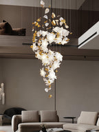 Over a low sofa in a living room with a mezzanine, this Clérachic chandelier hangs in a narrow S of white petals and gold leaves.