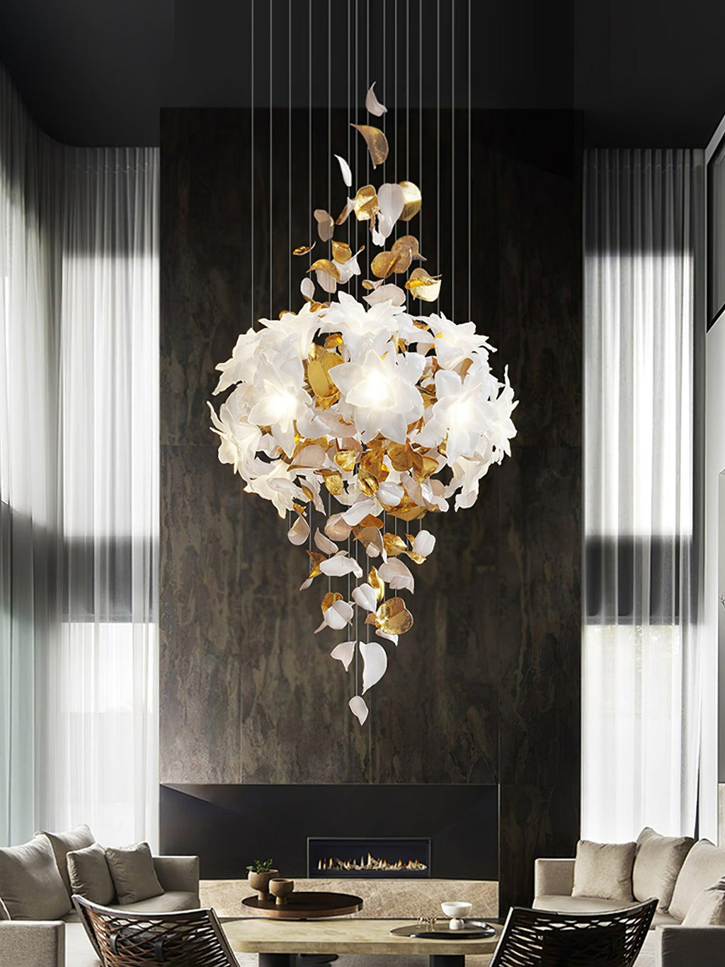 Over a dining table in front of a dark stone wall, this Clérachic chandelier shows a rounded cluster of petals above a drift of leaves.