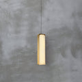 The Clérachic Gleam pendant lit head-on, its alabaster panel warm amber where light passes through the stone.