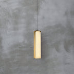 The Clérachic Gleam pendant lit head-on, its alabaster panel warm amber where light passes through the stone.