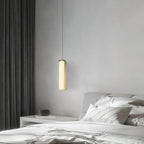 Clérachic Gleam pendant hung low beside a made bed, dropping a narrow pool of light onto the linen below.