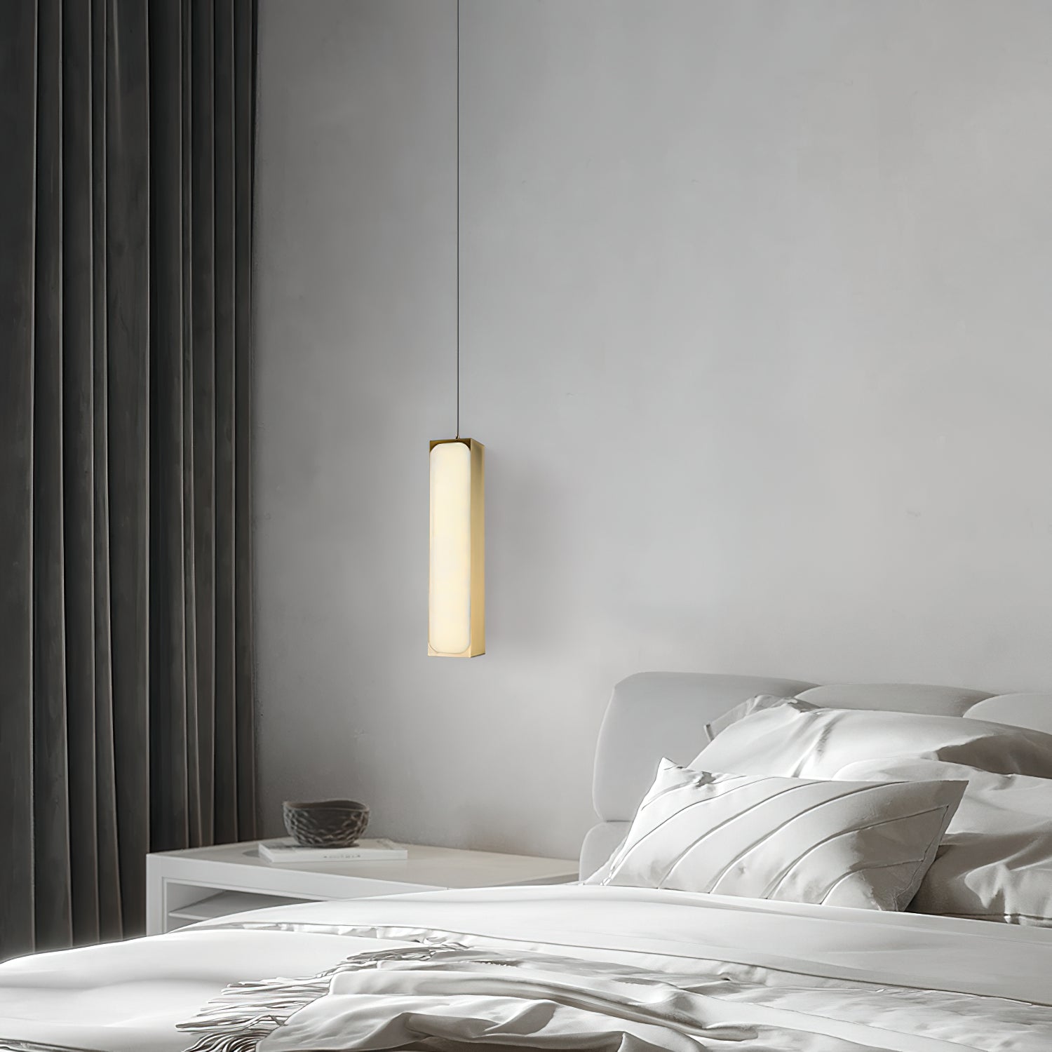 Clérachic Gleam pendant hung low beside a made bed, dropping a narrow pool of light onto the linen below.