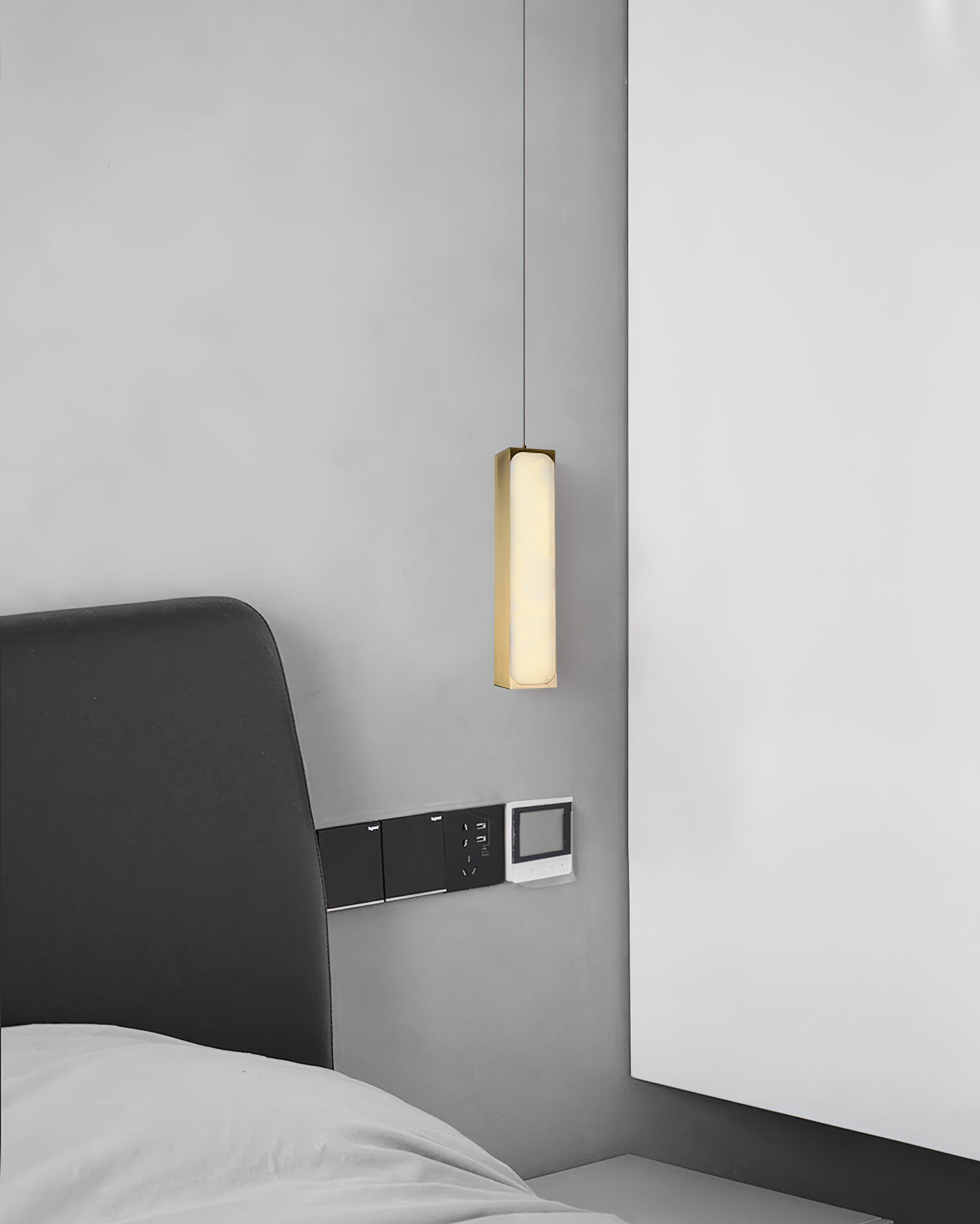 The Clérachic Gleam pendant dropped close to a headboard, its brass column reading as a slender sculpture.