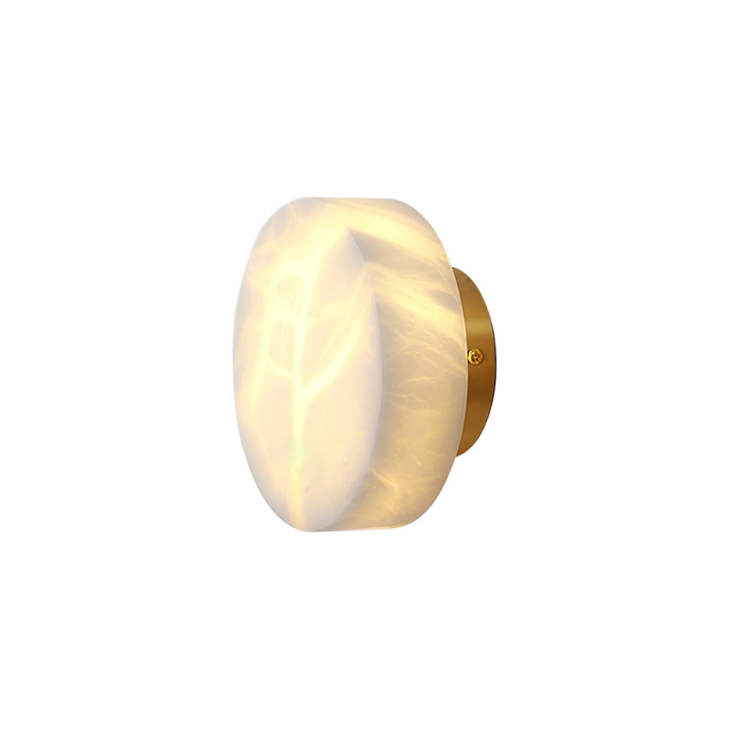 Studio view of the Clérachic Glim Round Alabaster Wall Sconce, brass backplate and lit alabaster drum shown against a plain background.