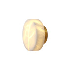 Studio view of the Clérachic Glim Round Alabaster Wall Sconce, brass backplate and lit alabaster drum shown against a plain background.