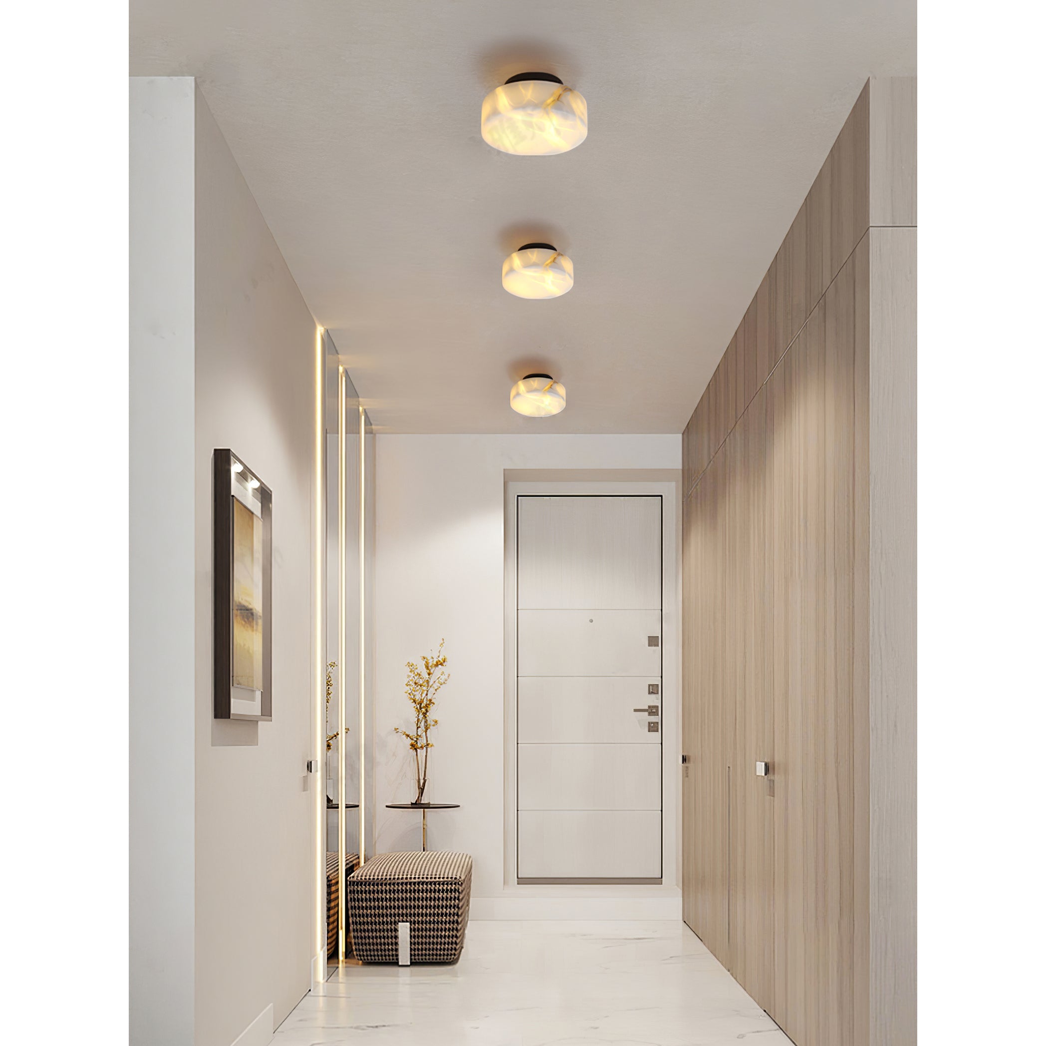 Three black-backed Clérachic Glim Round Alabaster Wall Sconces ceiling mounted in a line down a bright hallway toward the front door.