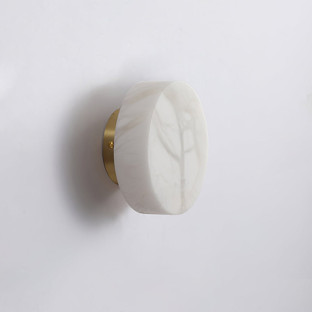 Unlit Clérachic Glim Round Alabaster Wall Sconce on a brass backplate, showing the cool grey markings in the natural alabaster.
