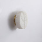 Unlit Clérachic Glim Round Alabaster Wall Sconce on a brass backplate, showing the cool grey markings in the natural alabaster.