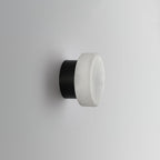 Unlit Clérachic Glim Round Alabaster Wall Sconce turned to show the black backplate the alabaster face closes over.