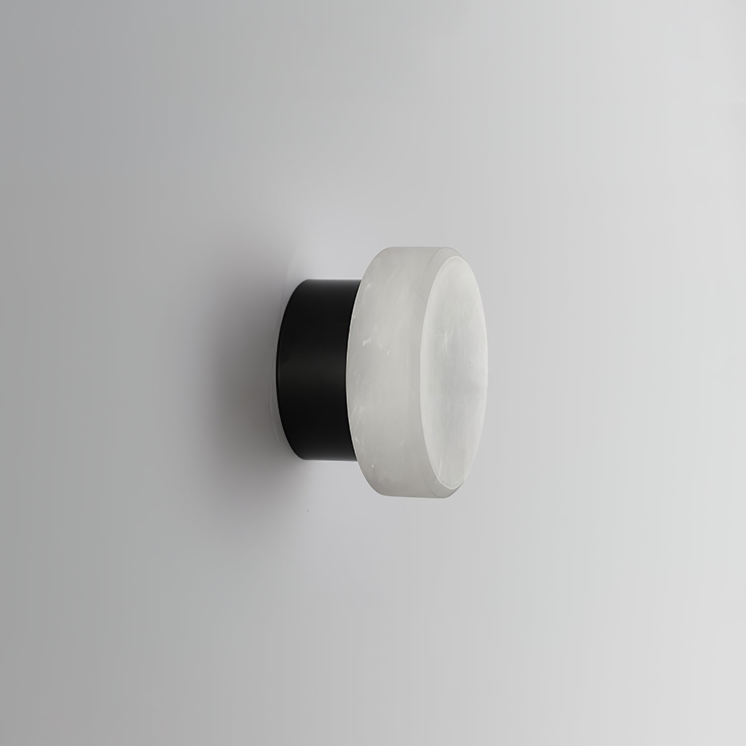 Unlit Clérachic Glim Round Alabaster Wall Sconce turned to show the black backplate the alabaster face closes over.