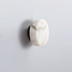 Clérachic Glim Round Alabaster Wall Sconce unlit in black, a crystalline amber seam running right across the natural stone face.