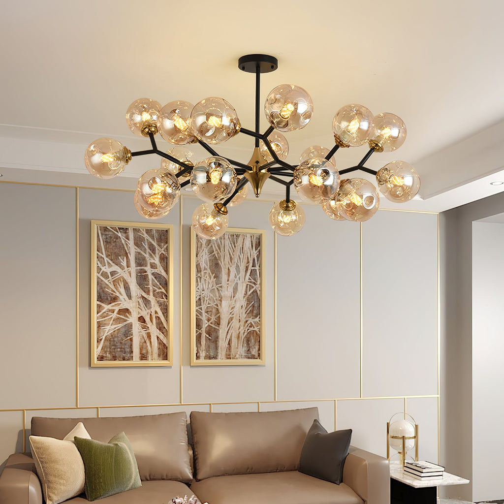 This Clérachic chandelier spreads amber glass globes across the ceiling above a taupe leather sofa and two tree-branch prints.