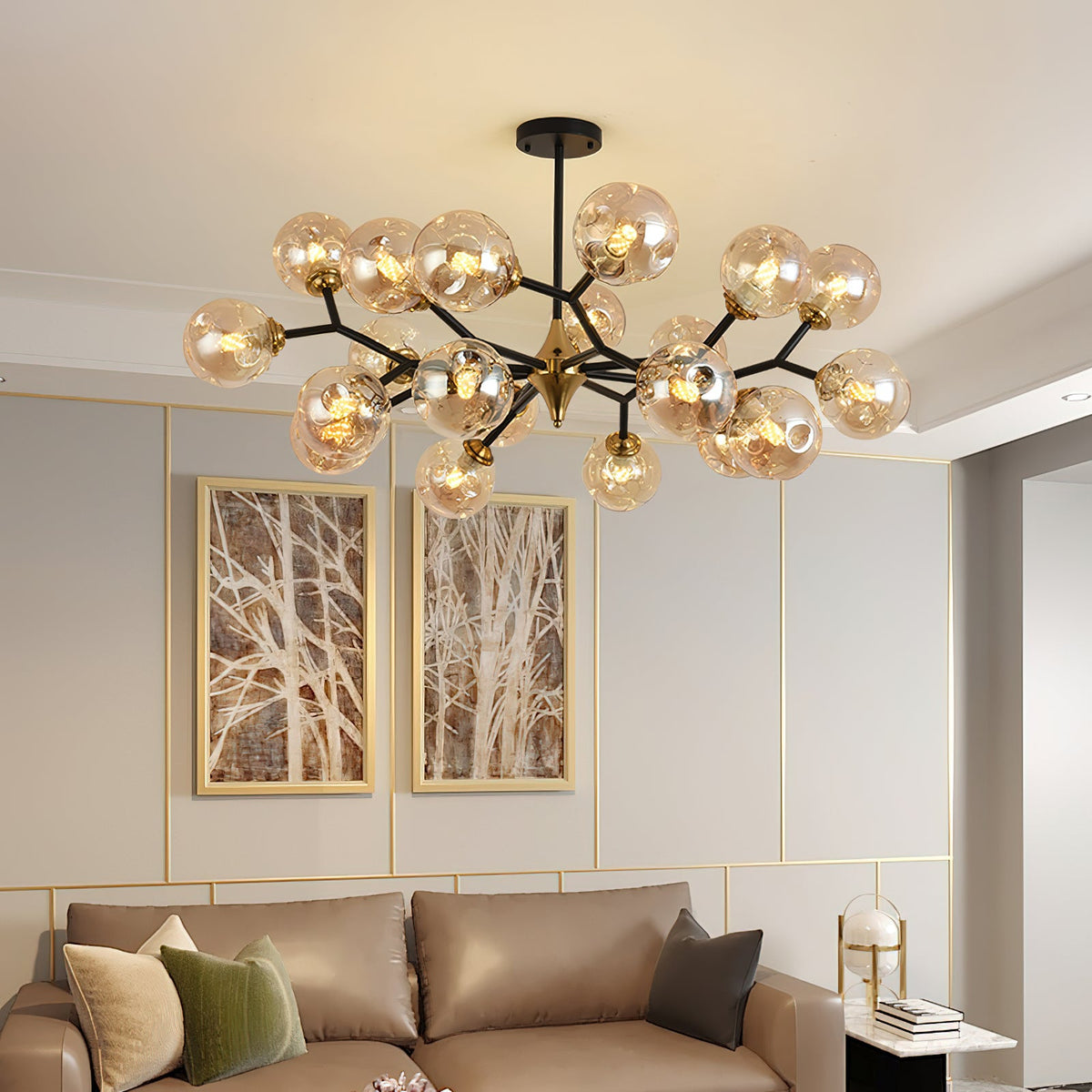 This Clérachic chandelier spreads amber glass globes across the ceiling above a taupe leather sofa and two tree-branch prints.