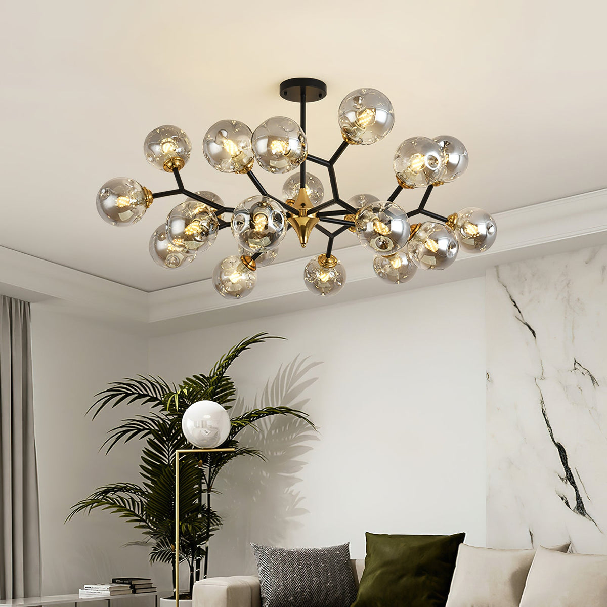 Smoky grey glass globes on black branches, this Clérachic chandelier hangs over a white marble feature wall and a tall palm.