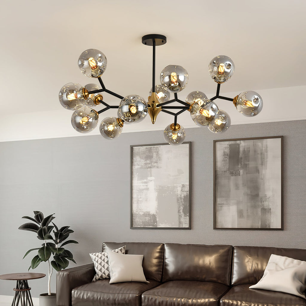 A Clérachic chandelier with smoky grey globes branches from a black rod above a brown leather sofa and two grey abstract prints.