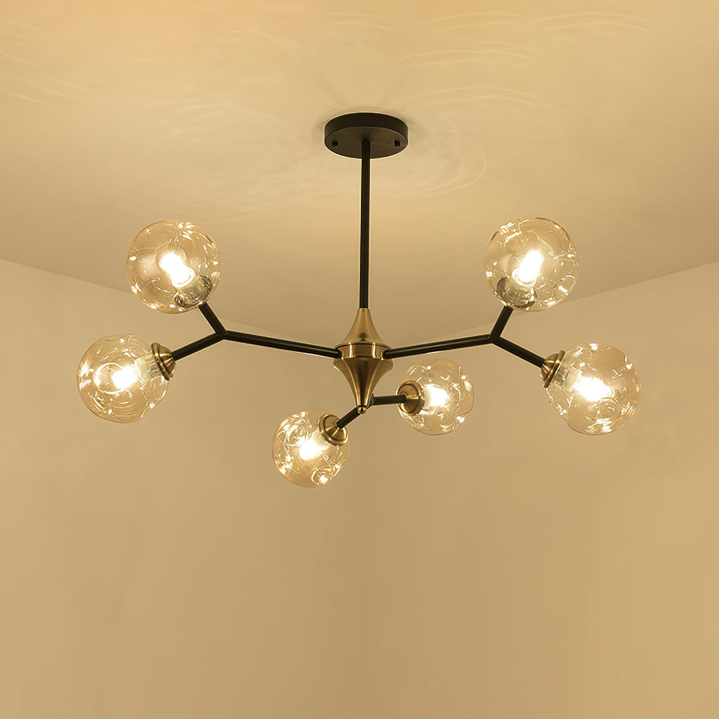 Amber Clérachic chandelier lit warm against a cream ceiling, its black arms and brass hub spreading into five arms.
