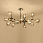 A Clérachic chandelier with amber globes in a double layer of black branches, glowing against a warm cream ceiling.