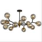 A smoky grey glass globe chandelier on black arms with a brass hub, this Clérachic ceiling light on a plain white backdrop.