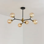 A small Clérachic chandelier with amber globes on five black arms hangs in a pale corner, a brass hub at its centre.