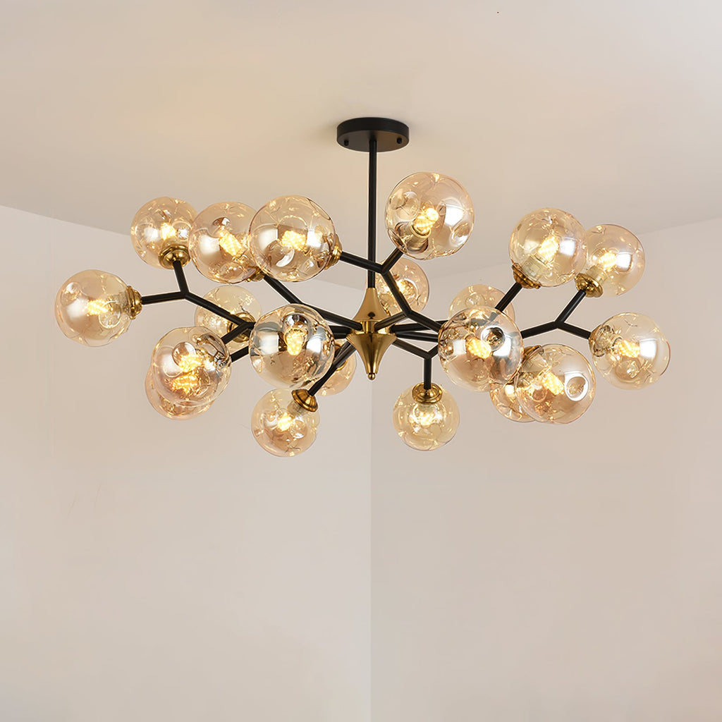 A large amber Clérachic chandelier lit warm, with globes crowded along its black branches around a brass centre.