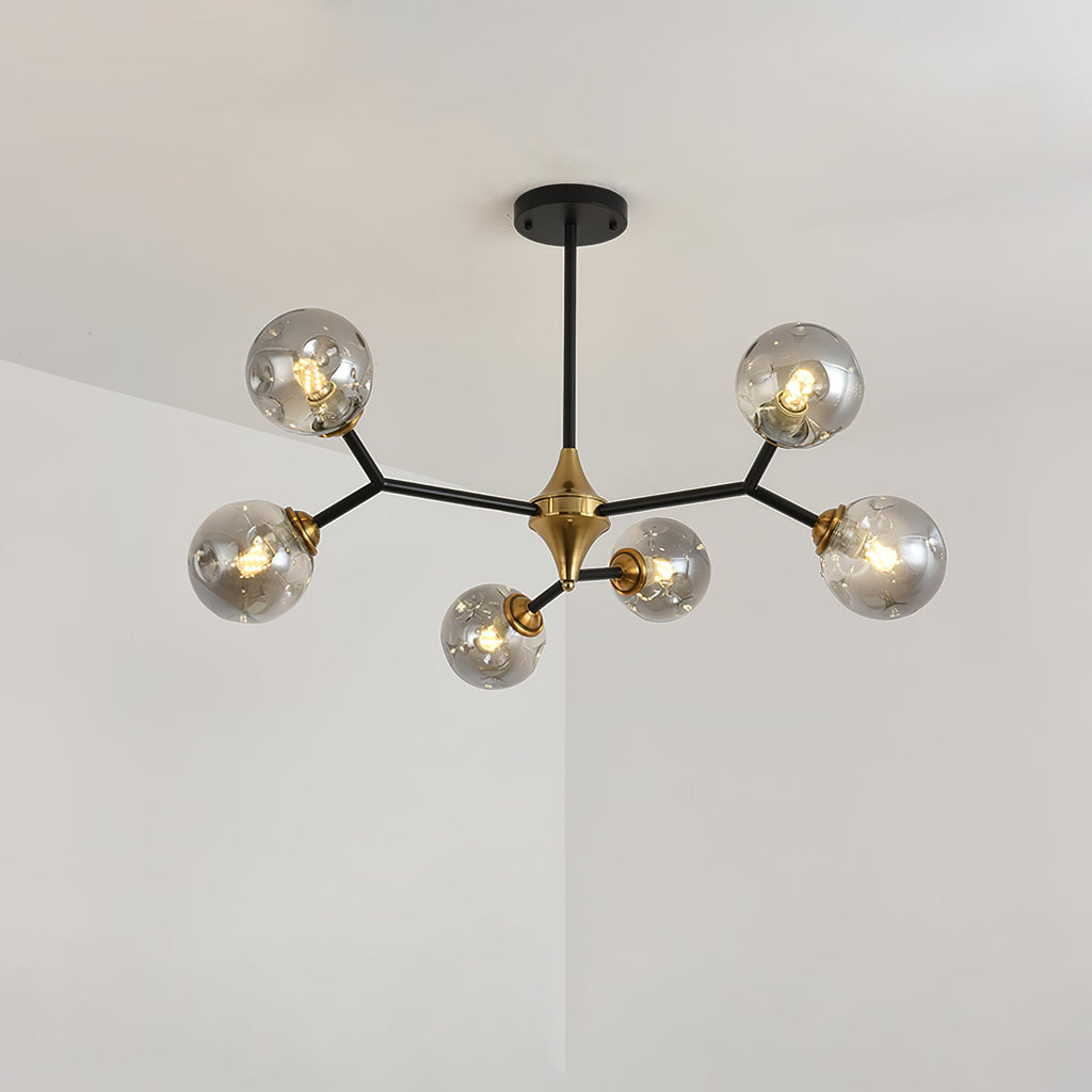 The smaller smoky grey Clérachic chandelier, with fewer globes on straight black arms, lit against a pale corner.