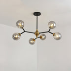The smaller smoky grey Clérachic chandelier, with fewer globes on straight black arms, lit against a pale corner.