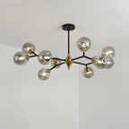 A smoky grey Clérachic chandelier with globes spread across black arms and a brass hub, lit and seen at a slight angle.