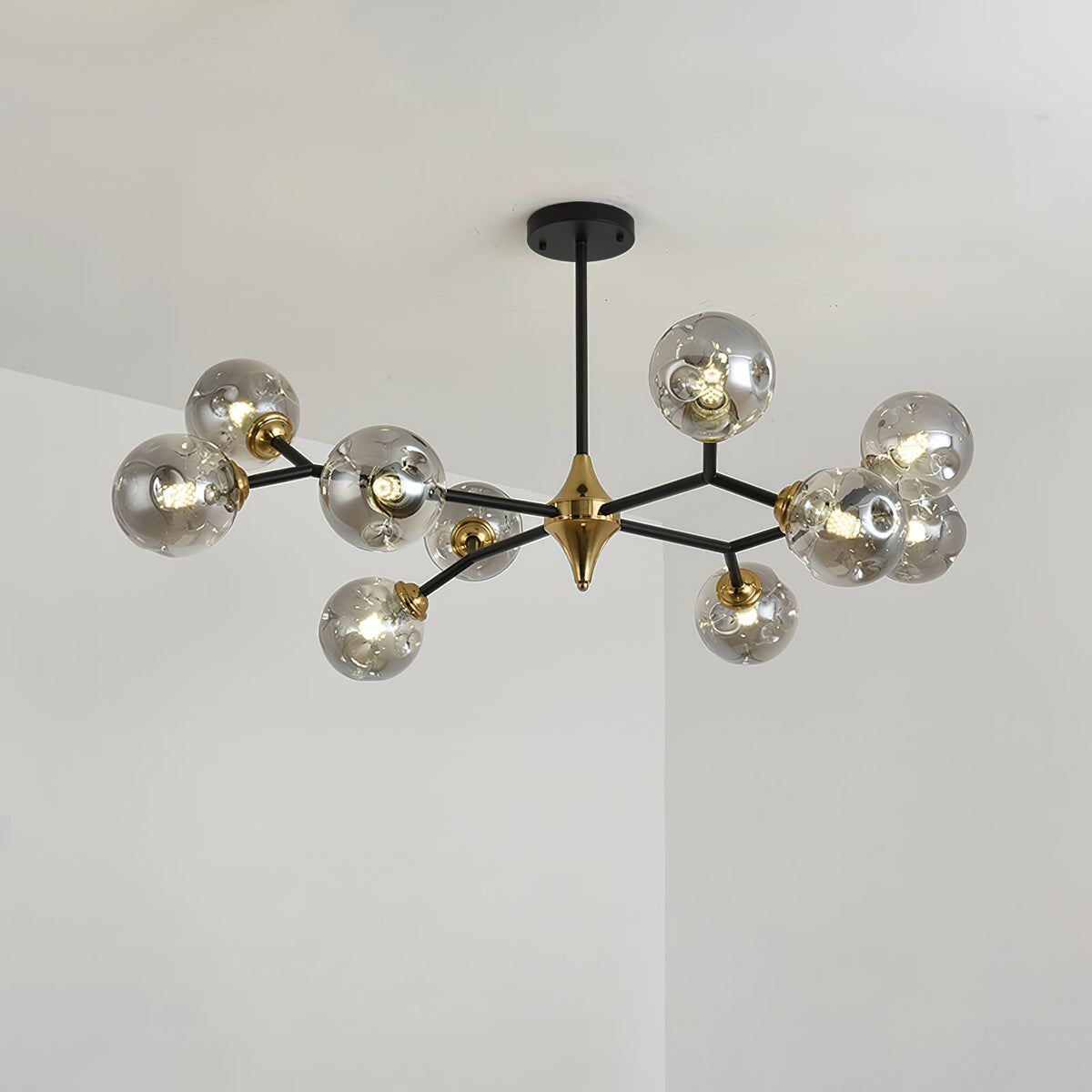 A smoky grey Clérachic chandelier with globes spread across black arms and a brass hub, lit and seen at a slight angle.