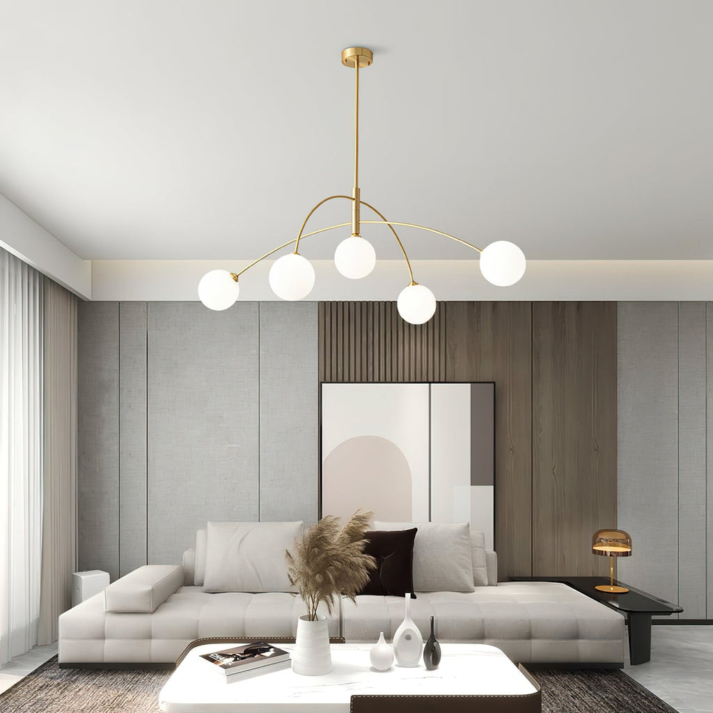 Gold and white Clérachic chandelier with arched arms over a pale sofa and a wood-slat feature wall in a living room.