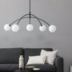 Black and white Clérachic chandelier with five globes on arched arms, hung above a charcoal sofa with linen cushions.