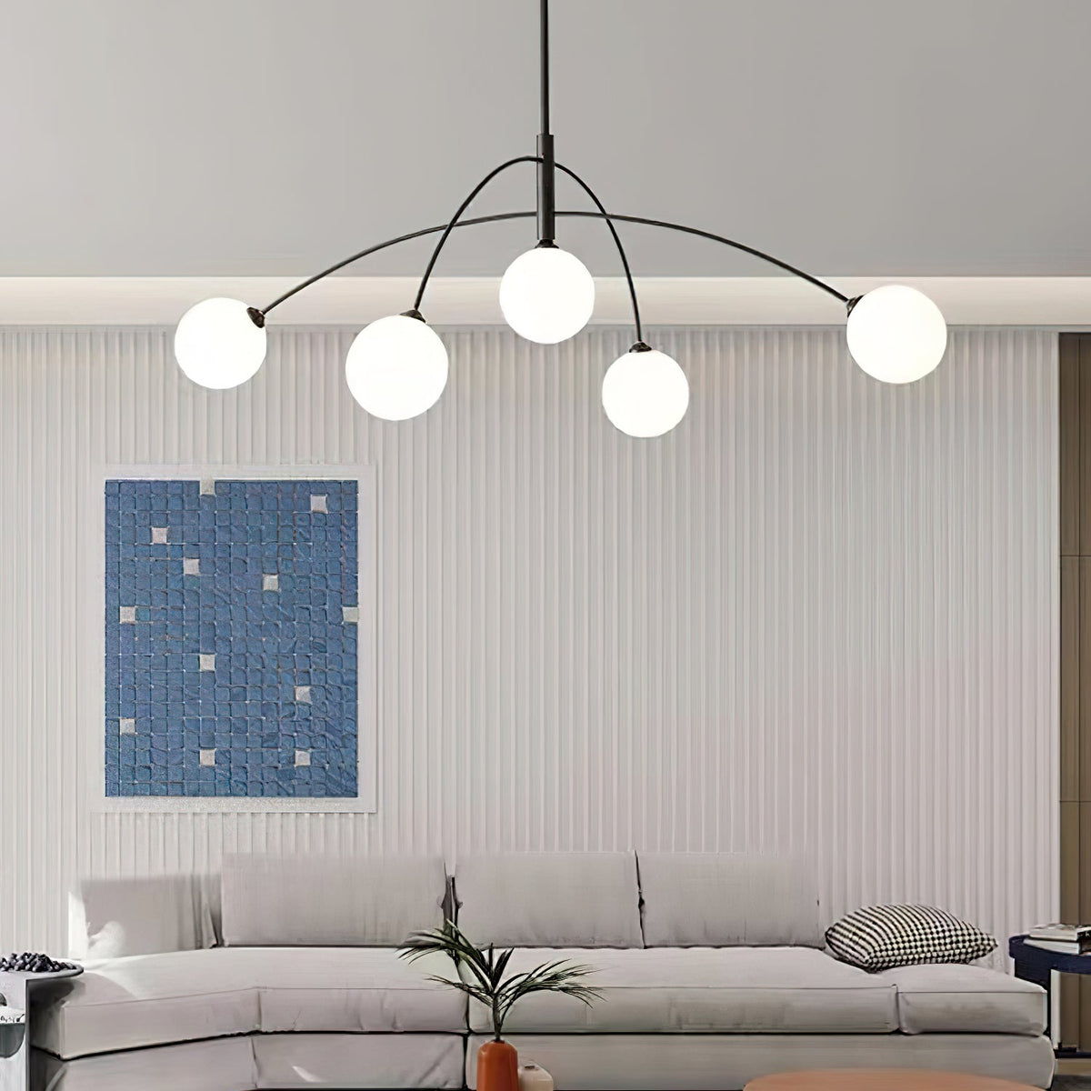 Black and white Clérachic chandelier over a pale sofa and a ribbed feature wall with a blue mosaic print.