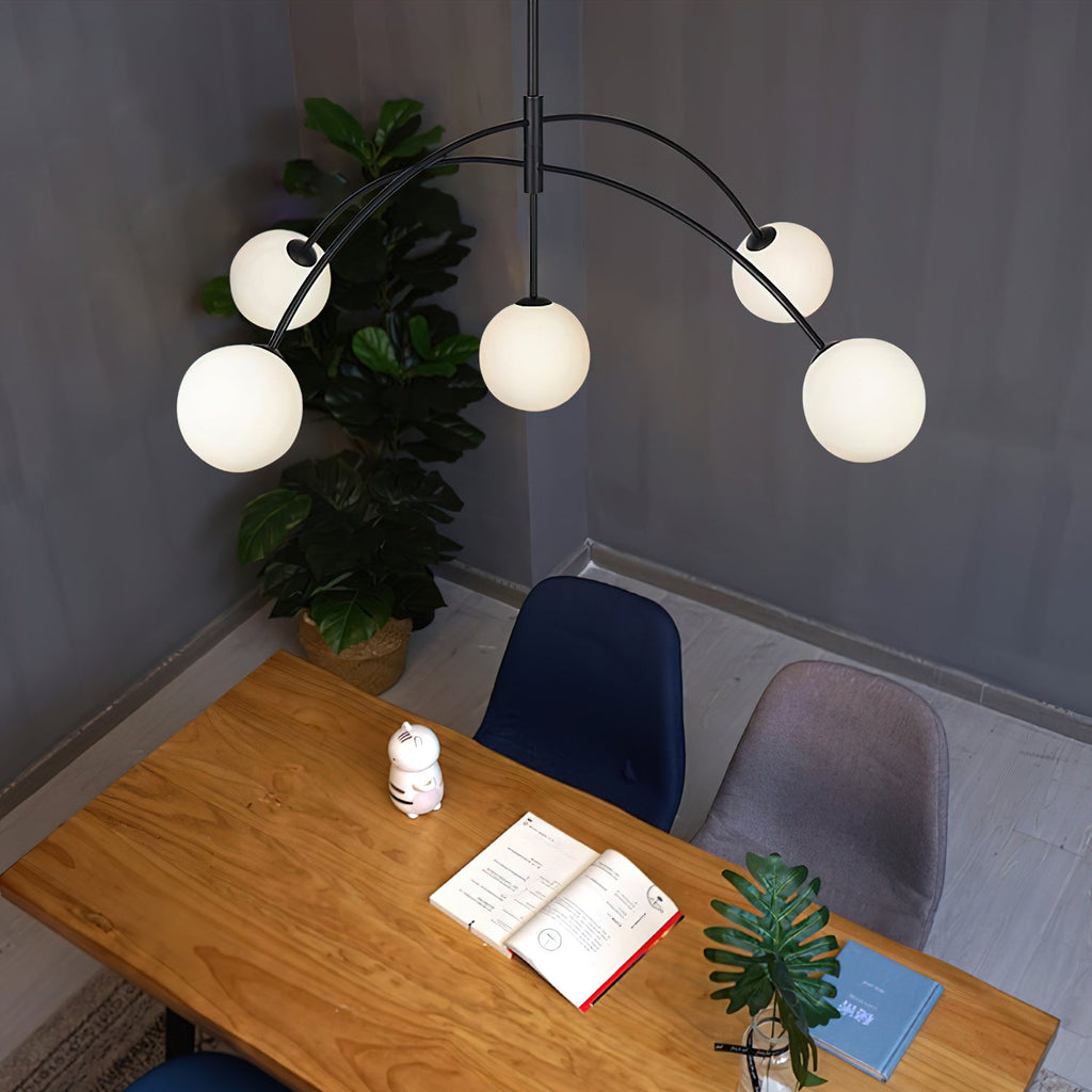 Black and white Clérachic chandelier seen from above, over a pine desk with an open book and a leafy plant.