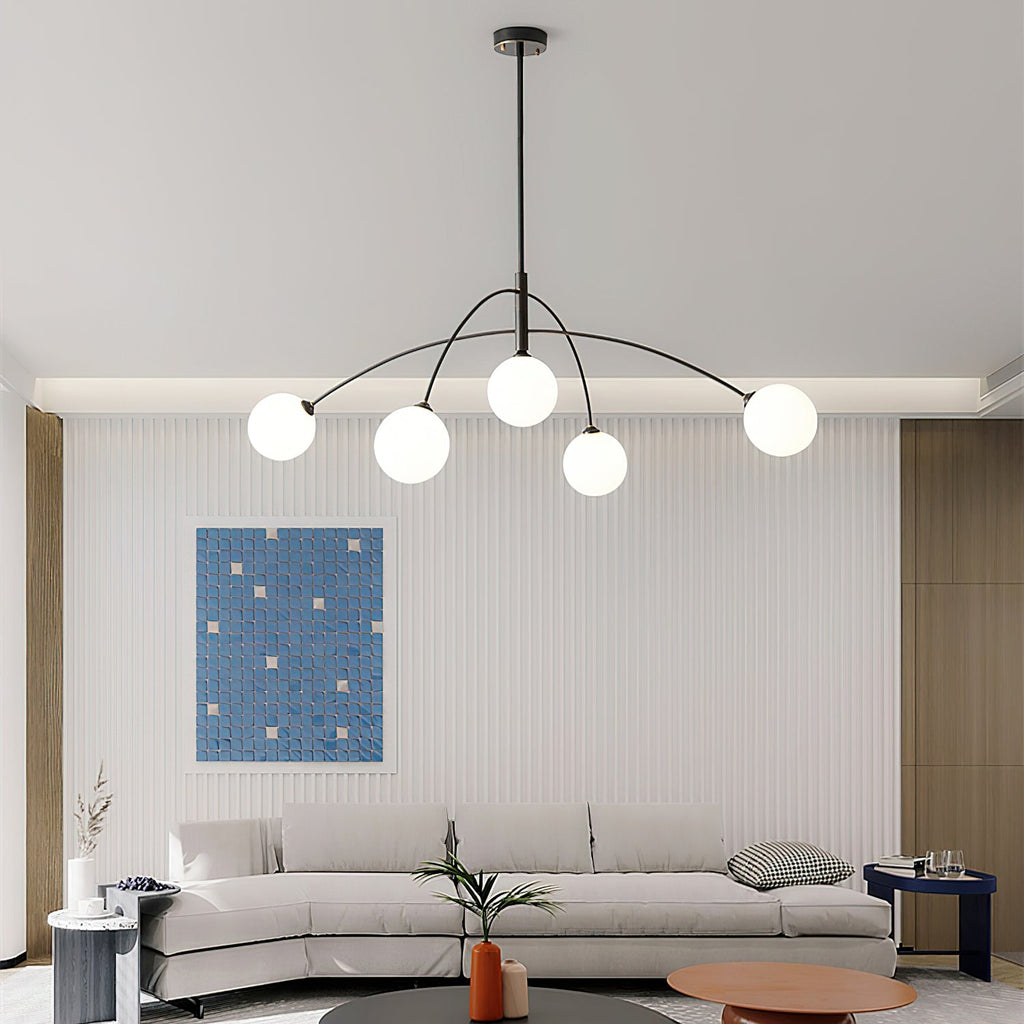 Black and white Clérachic chandelier lit above a sofa, with a ribbed wall and a blue mosaic print and a round wooden coffee table.